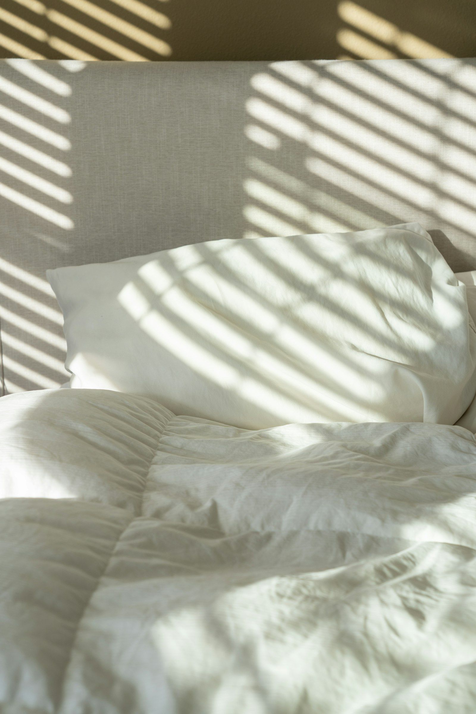Crisp white bed linen in soft morning light and shadow