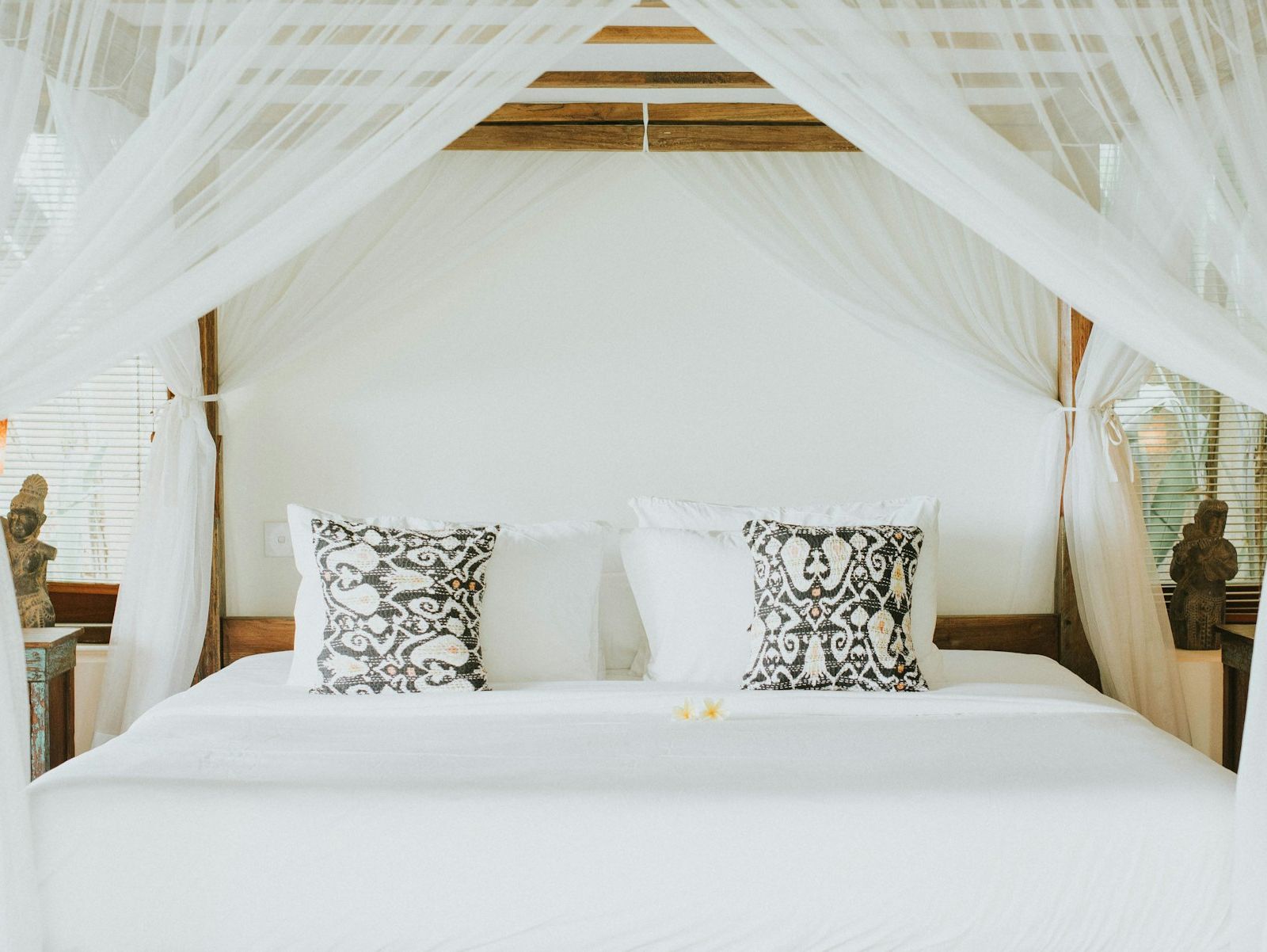 Bed with white linen under a light canopy