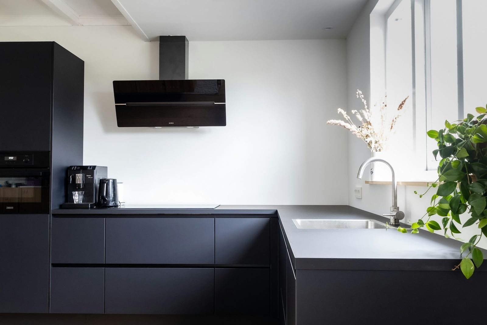 Modern kitchen with matte black cabinets and a white counter by the window