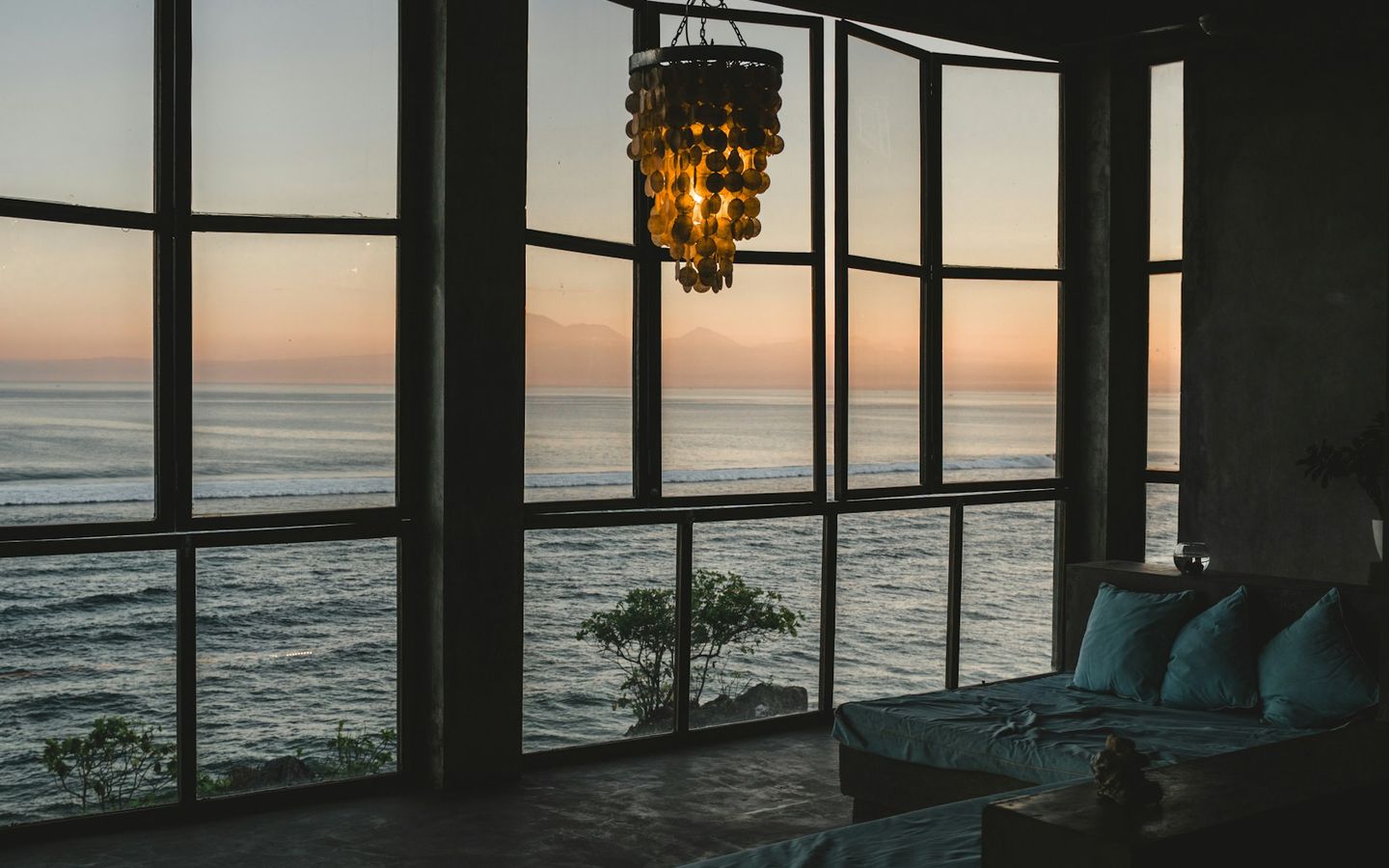 Lounge with tall windows looking out to the sea at sunset
