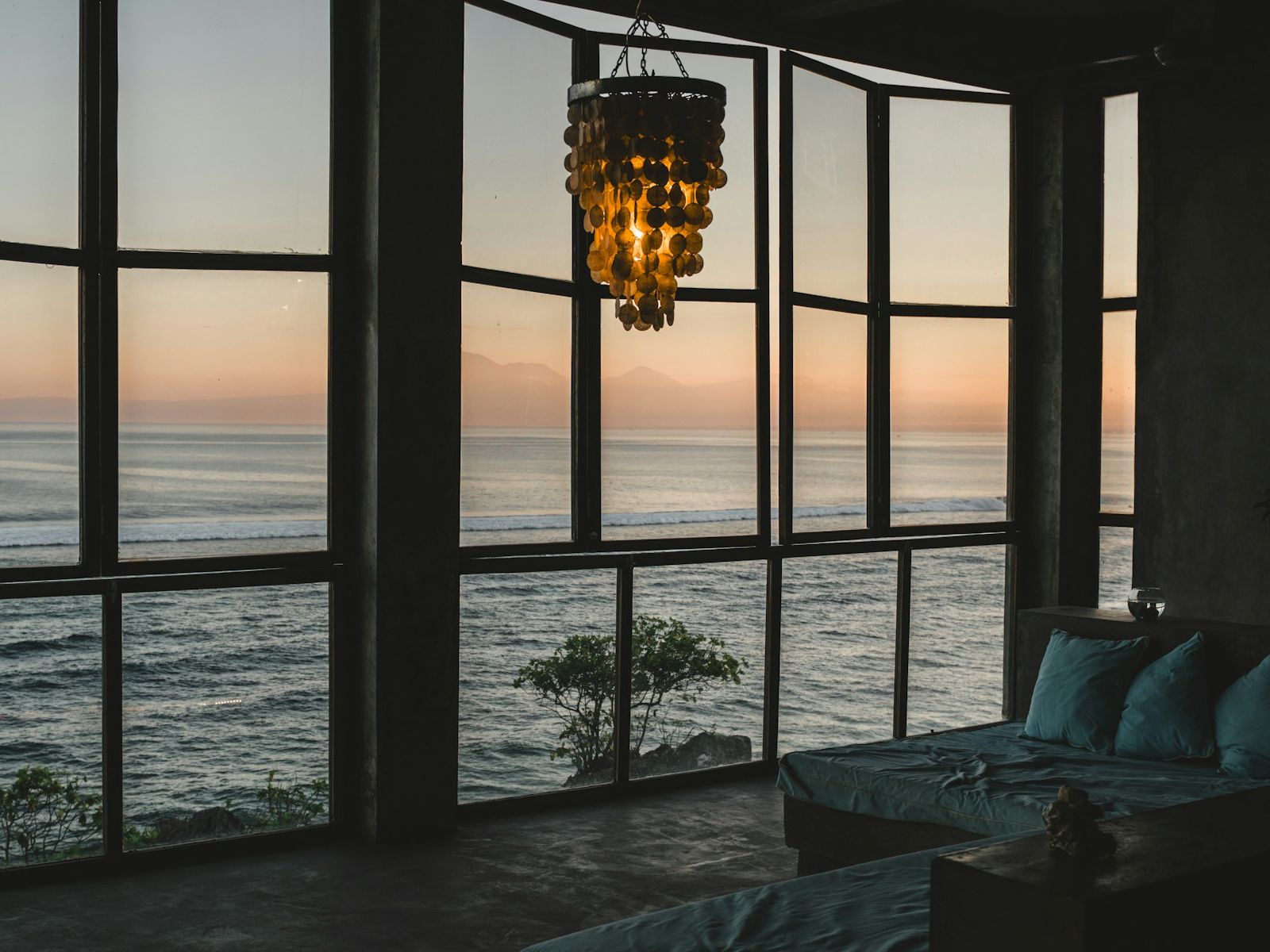 Lounge with tall windows looking out to the sea at sunset